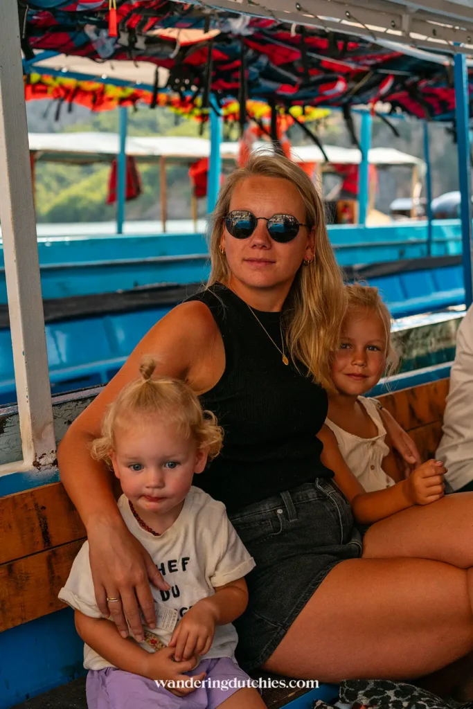 Moeder met twee jonge kinderen op een kleurrijke boot tijdens een boottocht naar de Shala-rivier in Albanië.