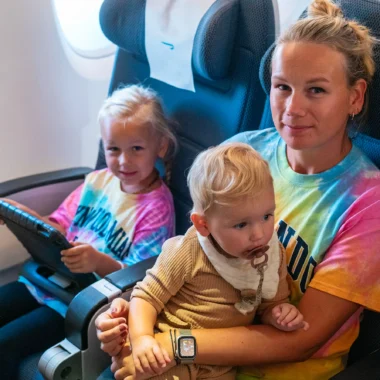 Moeder met twee jonge dochters in het vliegtuig op de terugweg van een rondreis door Florida, ontspannen genietend tijdens de vlucht.