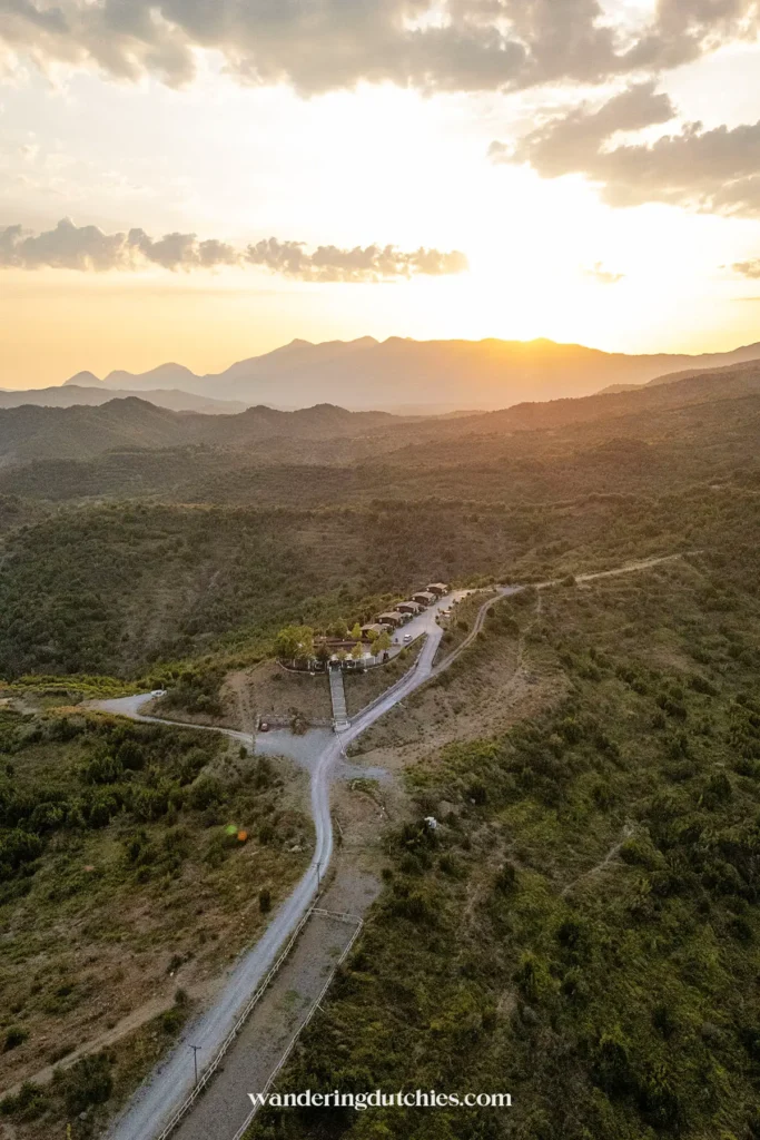 Zonsondergang boven een kronkelende bergweg in Albanië, perfect voor een roadtrip.