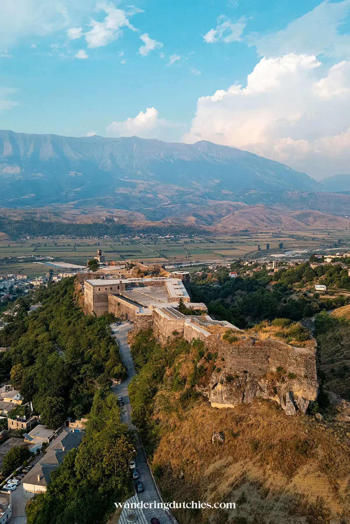 Dronebeeld van het imposante Gjirokastër Kasteel en het omliggende landschap in Albanië.