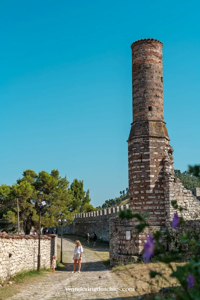 De historische rode moskee met omliggende kasteelmuren in Berat Castle, met een blauwe hemel op de achtergrond.