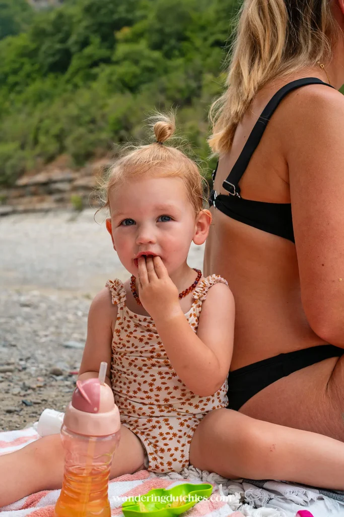 Kind geniet van een snack op een kiezelstrand bij Osumi Canyon.