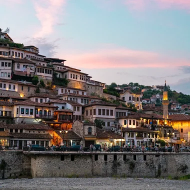 Berat, Albanië, bij zonsondergang met kleurrijke hemel en de verlichte huizen van de stad.