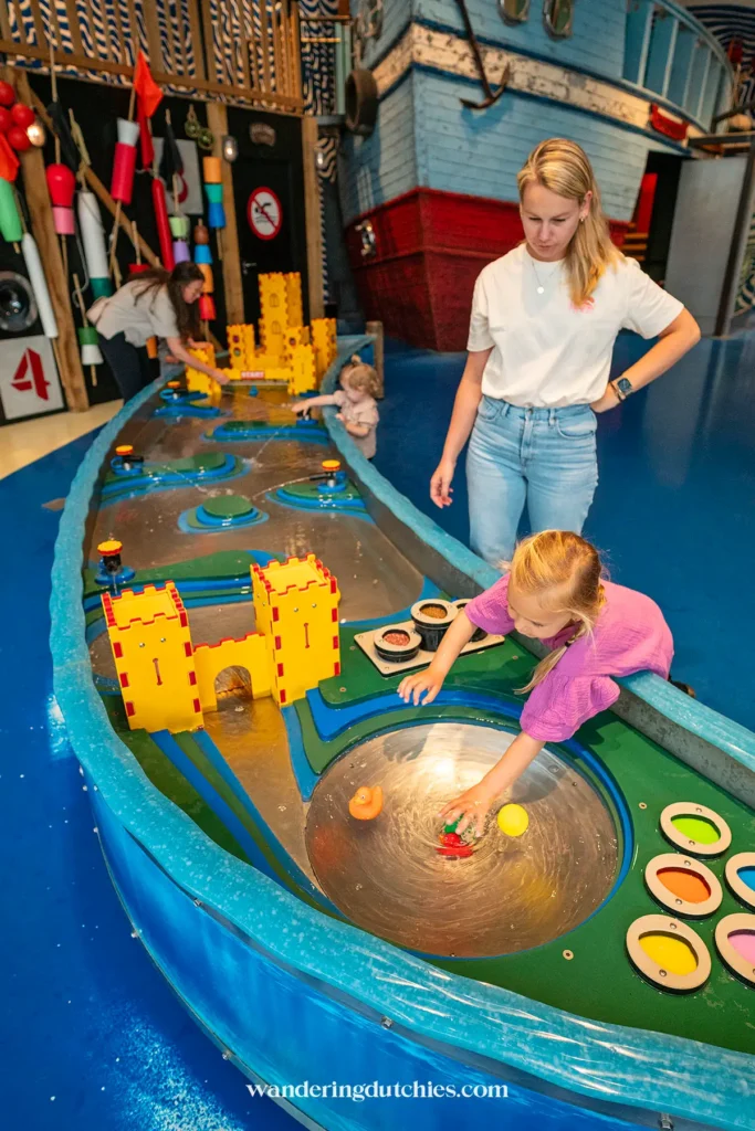Een moeder en haar kind spelen bij een waterkanaal in het Experimentarium in Kopenhagen.