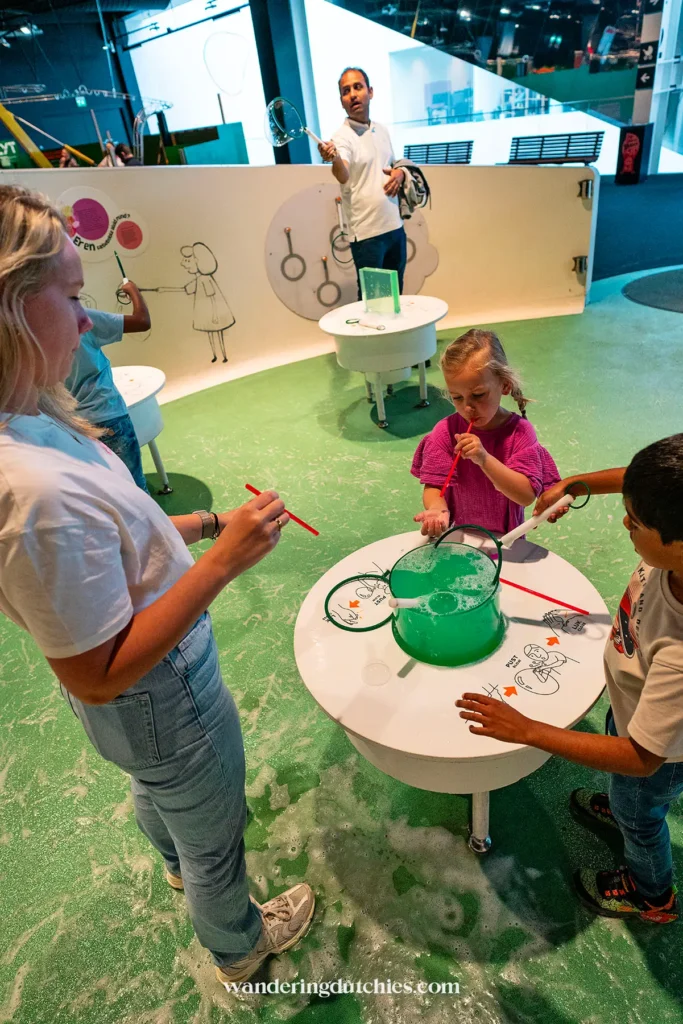 Een moeder en kind experimenteren met grote zeepbellen in een interactieve ruimte in het Experimentarium in Kopenhagen.