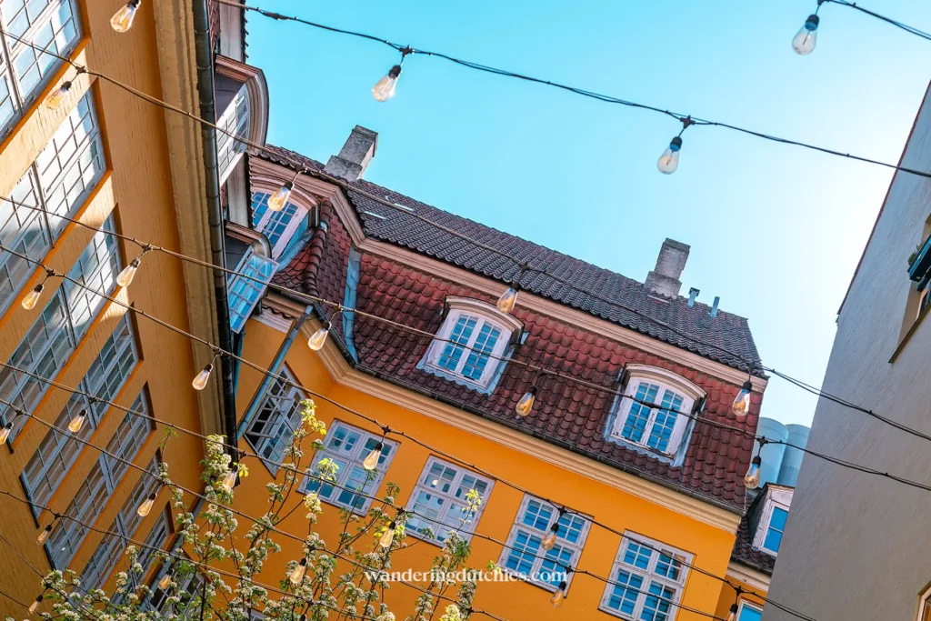 Kleurrijke gebouwen met lichtslingers tegen een blauwe lucht in Kopenhagen.