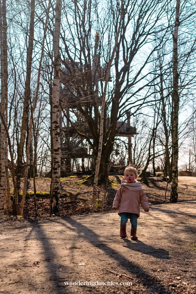 Child walking through the forest with a view of the lookout tower in the Troll Forest of De Schorre.
