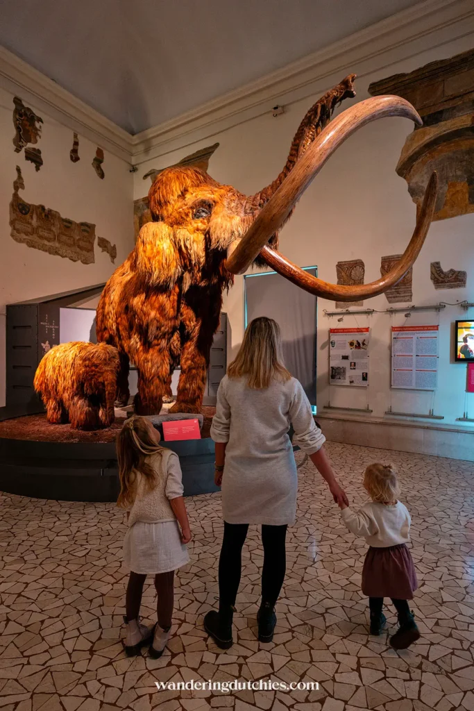 Moeder en kinderen voor de mammoet in het natuurhistorisch museum van Bergamo – een leerzaam en leuk uitje voor gezinnen.