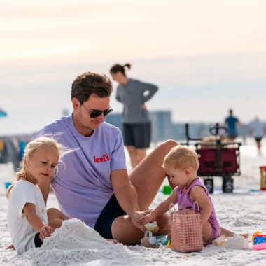 Een vader speelt samen met zijn twee kinderen met speelgoed op het strand tijdens hun reis door Florida.