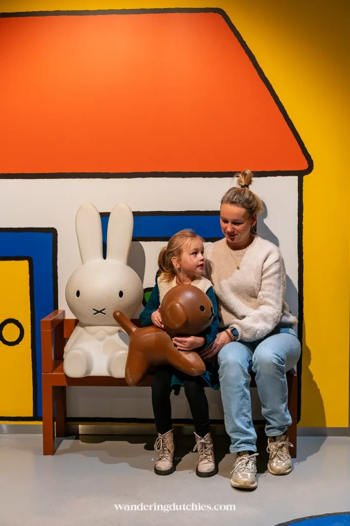 Moeder en dochter op een bankje bij nijntje en snuffie in het nijntje museum in Utrecht.