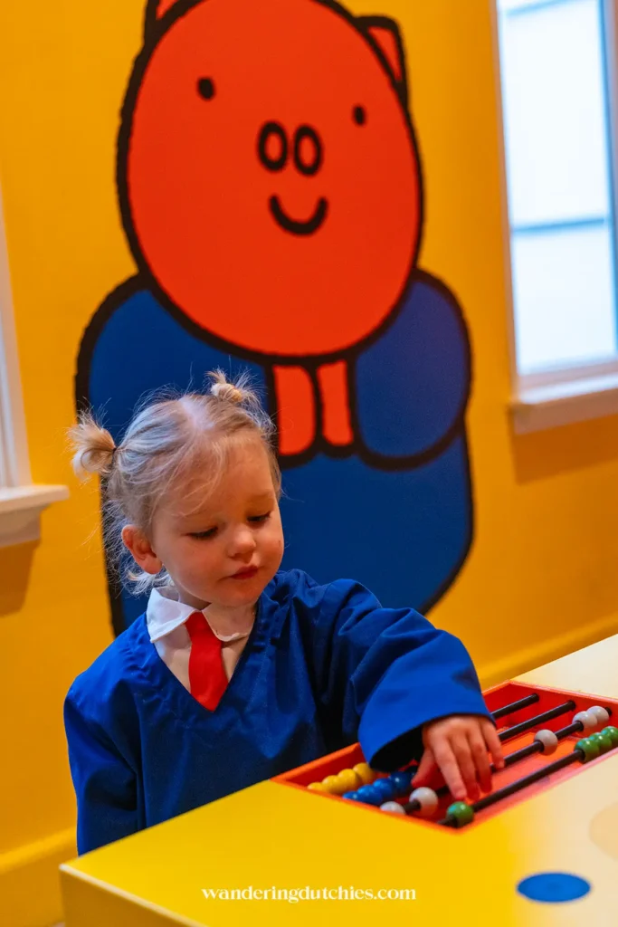 Klein meisje speelt met een telraam in de winkel van Betje Big in het nijntje museum.