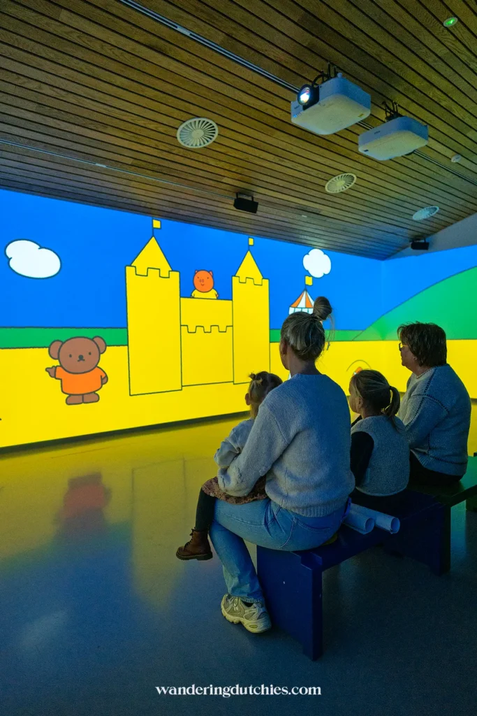 Familie kijkt naar een geprojecteerde nijntje-film in de projectiezaal van het nijntje museum.