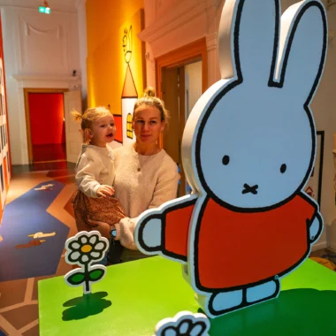 Moeder en kind in het nijntje museum in Utrecht, omringd door kleurrijke illustraties van Dick Bruna. Het leukste museum voor peuters en kleuters.