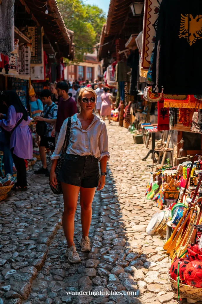Vrouw wandelt door de oude bazaar van Krujë in Albanië, omringd door kleurrijke souvenirwinkeltjes.