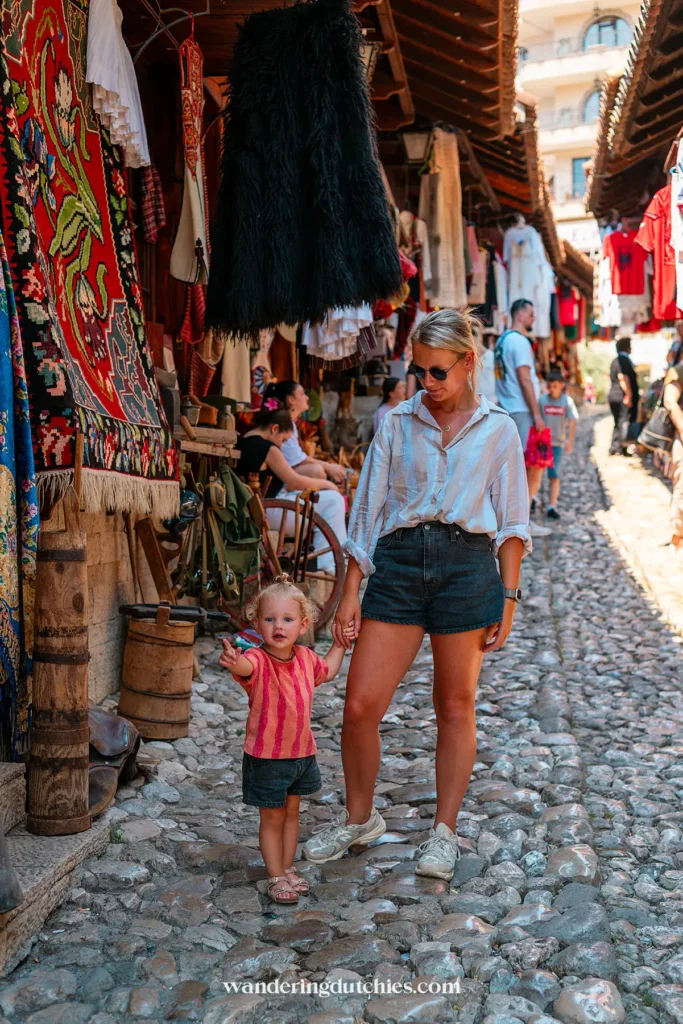 Moeder en peuter wandelen samen door de kleurrijke bazaar van Krujë in Albanië.