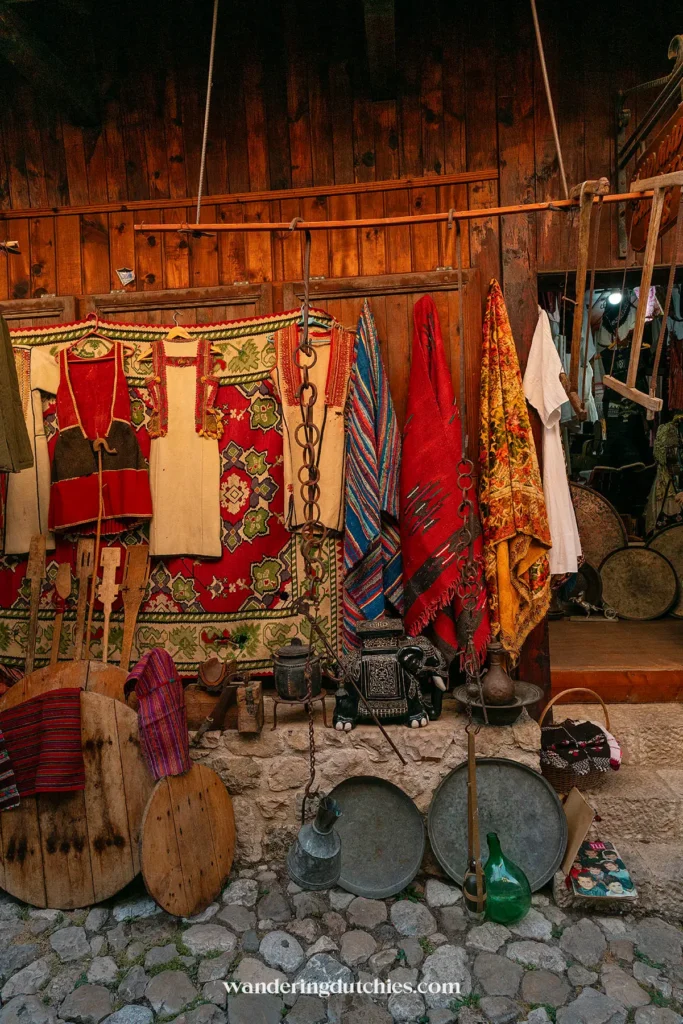 Traditionele kleding en gebruiksvoorwerpen aan de gevel van een winkeltje in Krujë, Albanië.