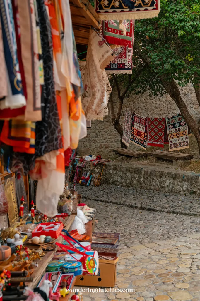 Kleurrijke tapijten en souvenirs in de schaduw van de bazaar van Krujë, Albanië.