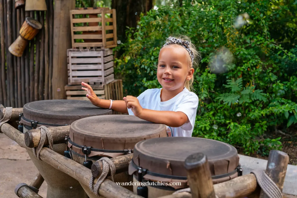 Kind geniet van het bespelen van traditionele trommels in de Afrikaanse themagebied van het park.