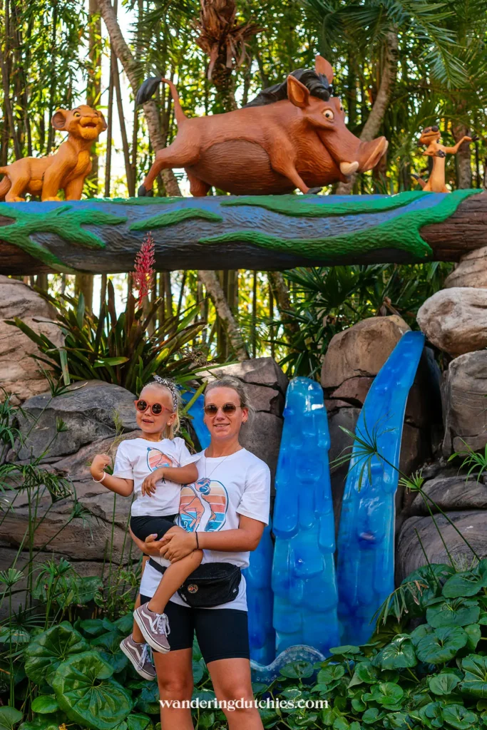Moeder en dochter poseren onder decor met Simba, Pumbaa en Timon in Animal Kingdom.