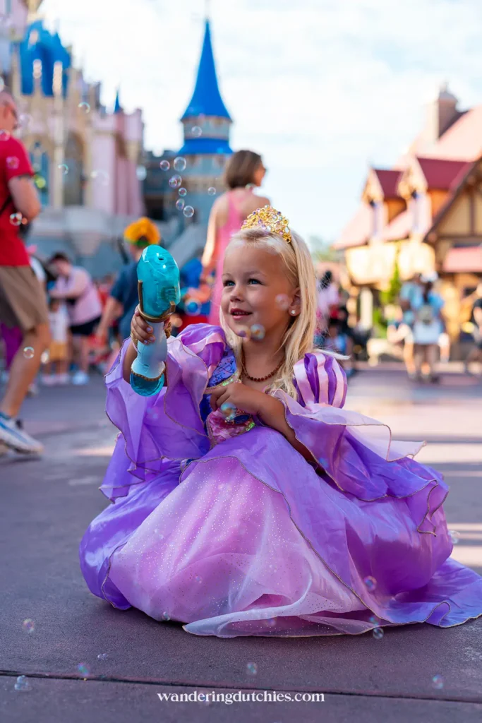 Klein meisje in prinsessenjurk speelt met bellenblazer in Magic Kingdom Orlando, vlak bij het kasteel.