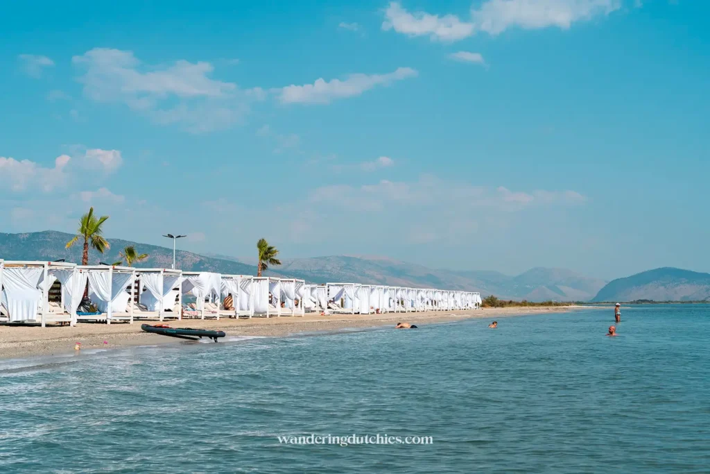 Luxe strandbedjes met witte doeken aan zee in Ksamil, Albanië – kosten voor strandbedjes kunnen hier oplopen tot €25 à €30 per dag.