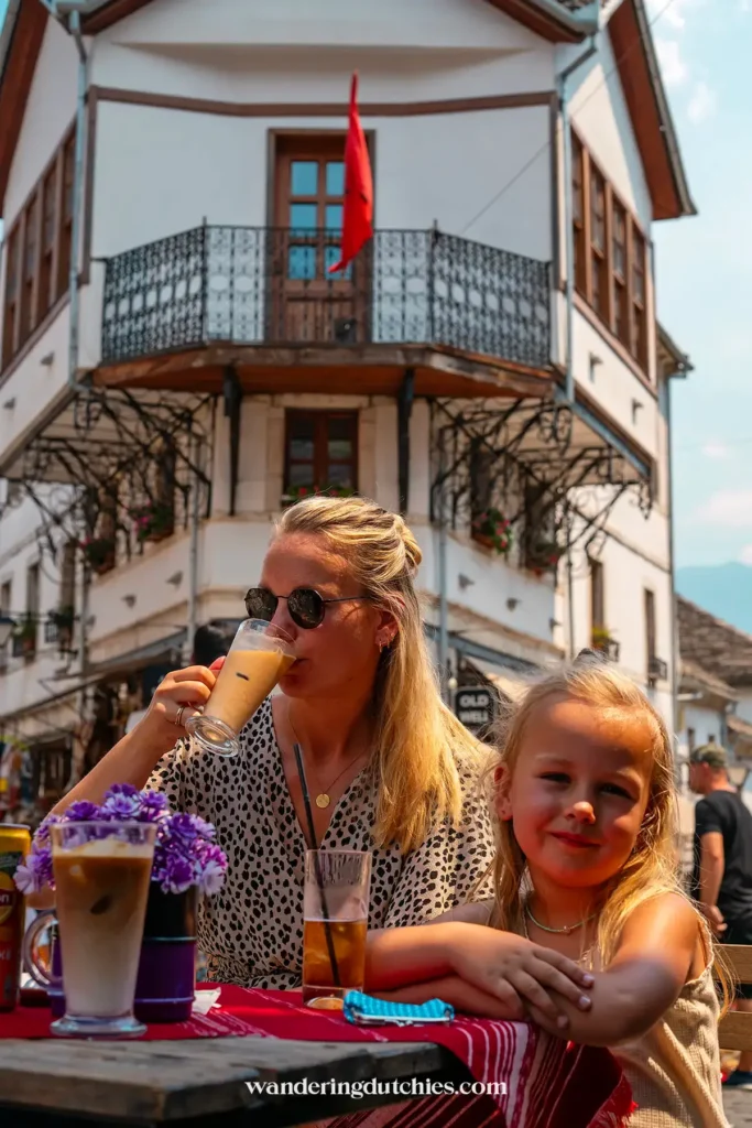 Moeder en dochter drinken ijskoffie en ijsthee op een terras in de oude bazaar van Gjirokaster, Albanië