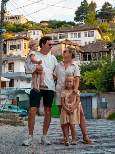Gezin met jonge kinderen in traditionele straat van Berat, Albanië, met historische huizen op de achtergrond tijdens hun roadtrip door Albanië