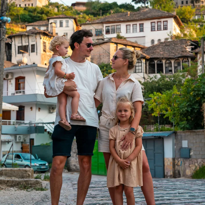 Gezin met jonge kinderen in traditionele straat van Berat, Albanië, met historische huizen op de achtergrond tijdens hun roadtrip door Albanië