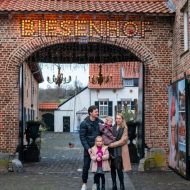 Gezin bij de ingang van restaurant Biesenhof in Geleen, onder sfeervolle poort met lichtletters