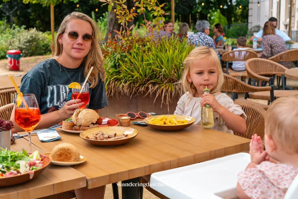 Moeder en kinderen lunchen op het terras van Kanjel in Maastricht met kindvriendelijke gerechten zoals frietjes en appelsap