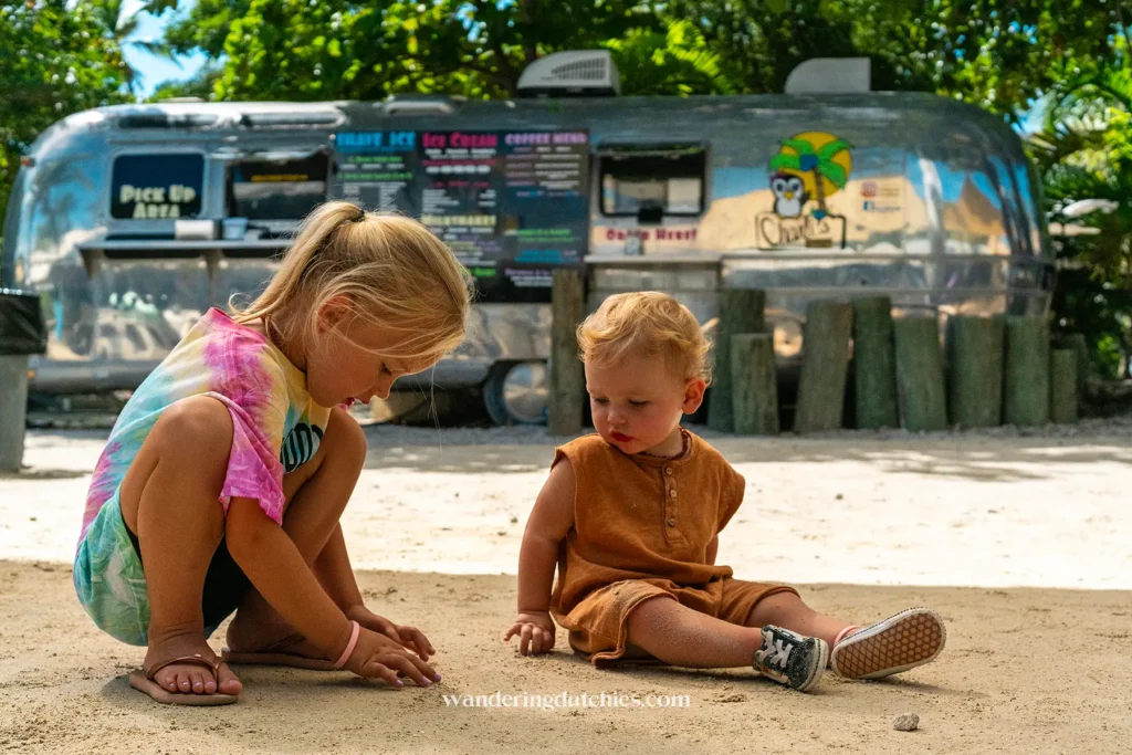 Twee jonge kinderen spelen in het zand voor een zilveren foodtruck met ijsjes in de Florida Keys