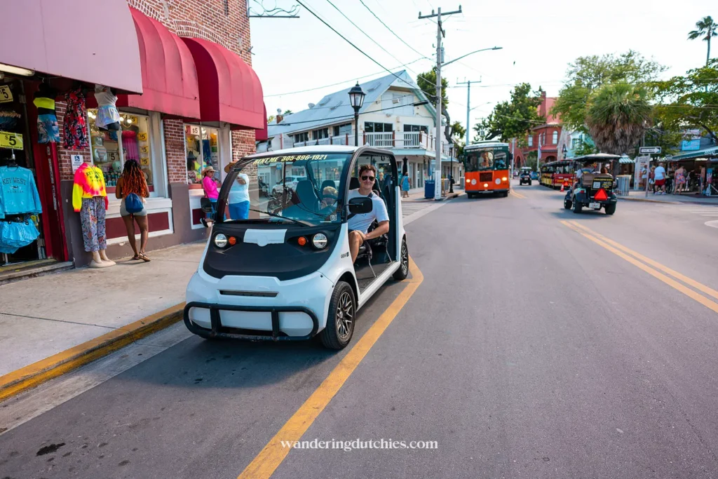 Man rijdt in een elektrische buggy door de straten van Key West in de Florida Keys, langs winkels en toeristen