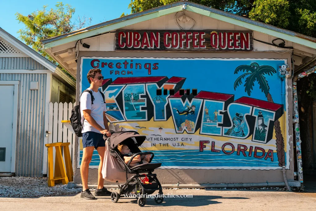 Vader met kinderwagen loopt langs de bekende Key West muurschildering bij Cuban Coffee Queen in de Florida Keys