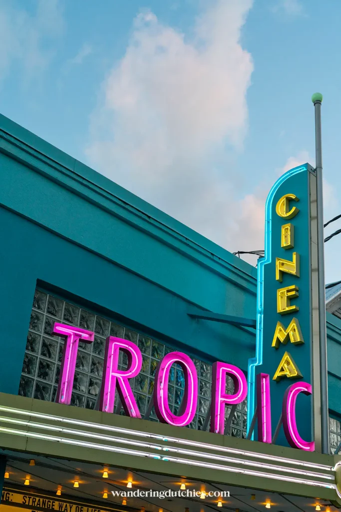 Neonbord van Tropic Cinema in Key West, gele CINEMA-toren en roze TROPIC-letters tegen blauwe lucht.