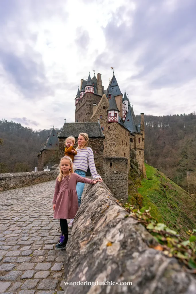 Mother and two children posing in front of Burg Eltz in Germany.