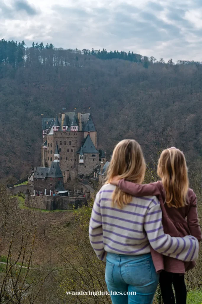 Mother and daughter looking out over Burg Eltz from a viewpoint in the forest.