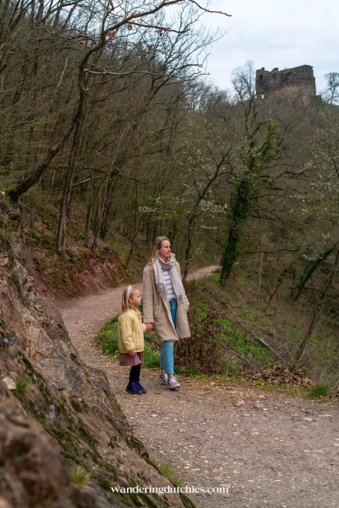 Mother and daughter walking along a forest path with views of the ruins near Burg Eltz.