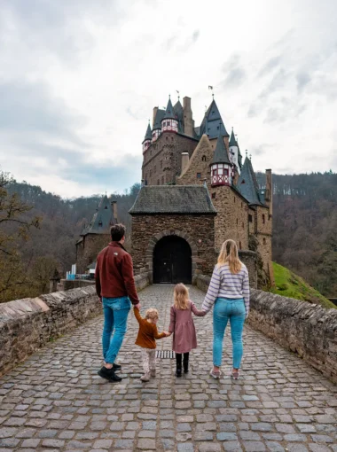 Family walking across the bridge to Burg Eltz, a fairytale castle in Germany and a popular outing in the Moselle region.