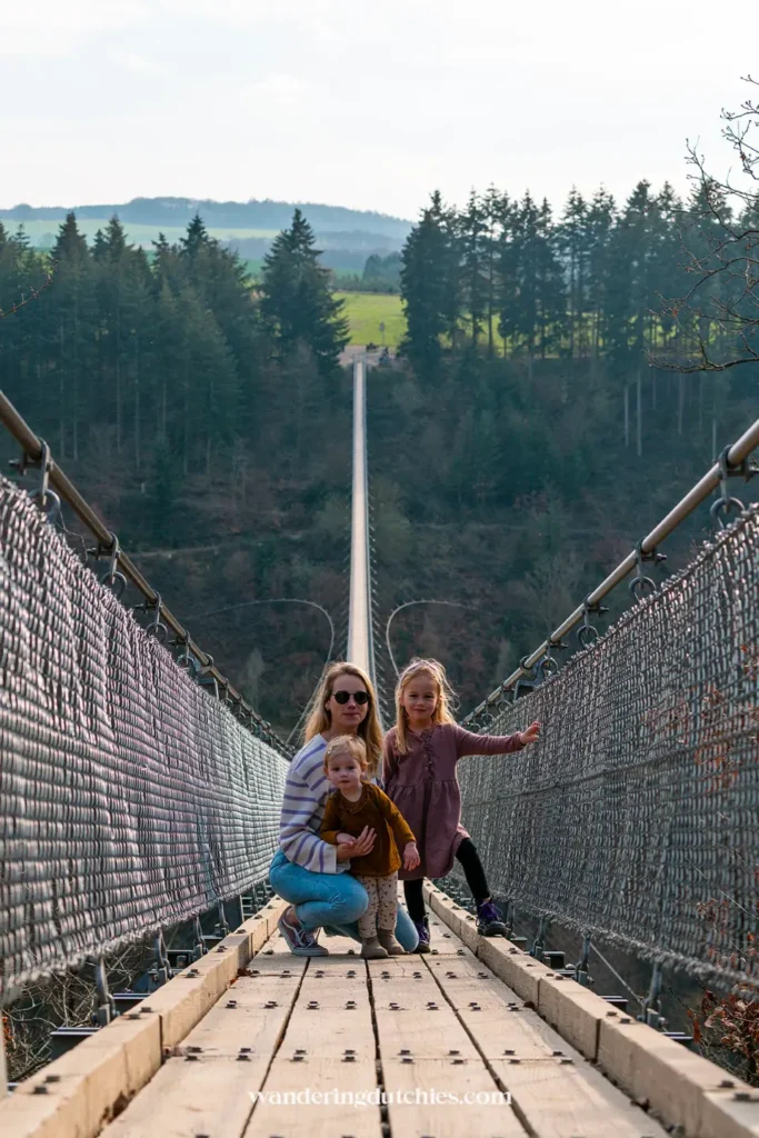 Mother with two children on the Geierlay Suspension Bridge in Germany, one of the longest suspension bridges in Europe.