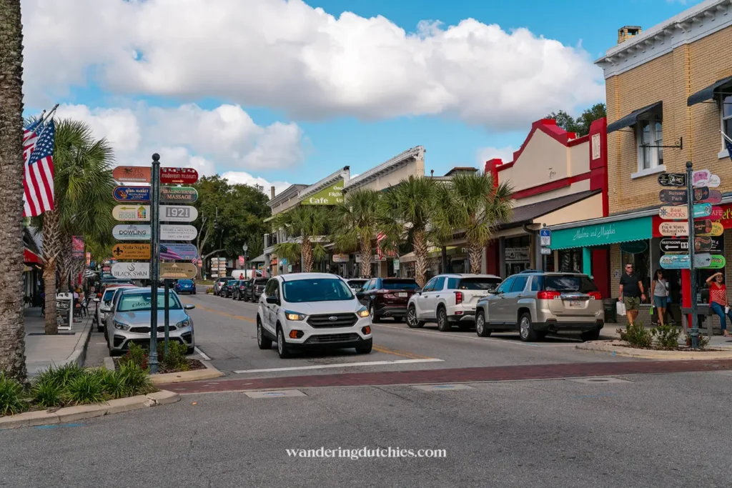 Witte huurauto rijdt door gezellig stadje met palmbomen en winkels in Florida