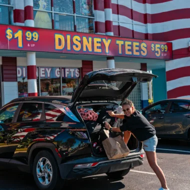 Auto huren en autorijden in Florida tijdens roadtrip, vrouw laadt koffers in huurauto bij Disney winkel in Orlando