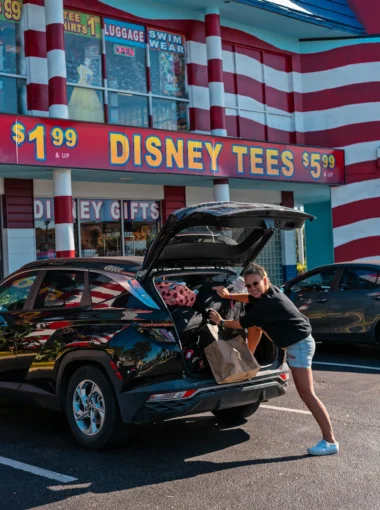 Auto huren en autorijden in Florida tijdens roadtrip, vrouw laadt koffers in huurauto bij Disney winkel in Orlando