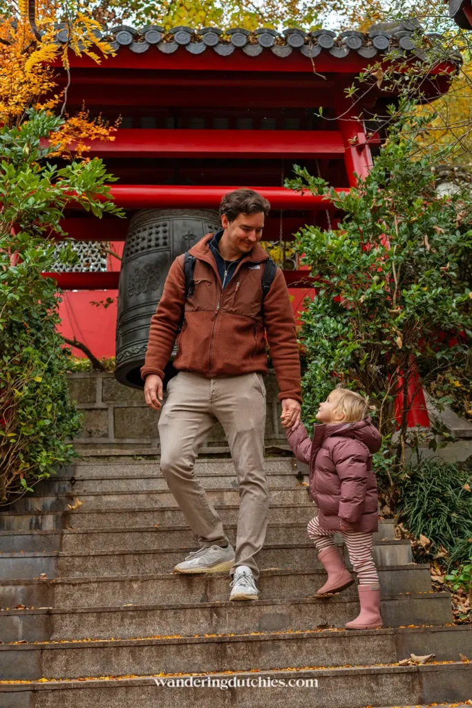 Vader en dochter lopen samen de trap af bij de rode tempel in Pairi Daiza