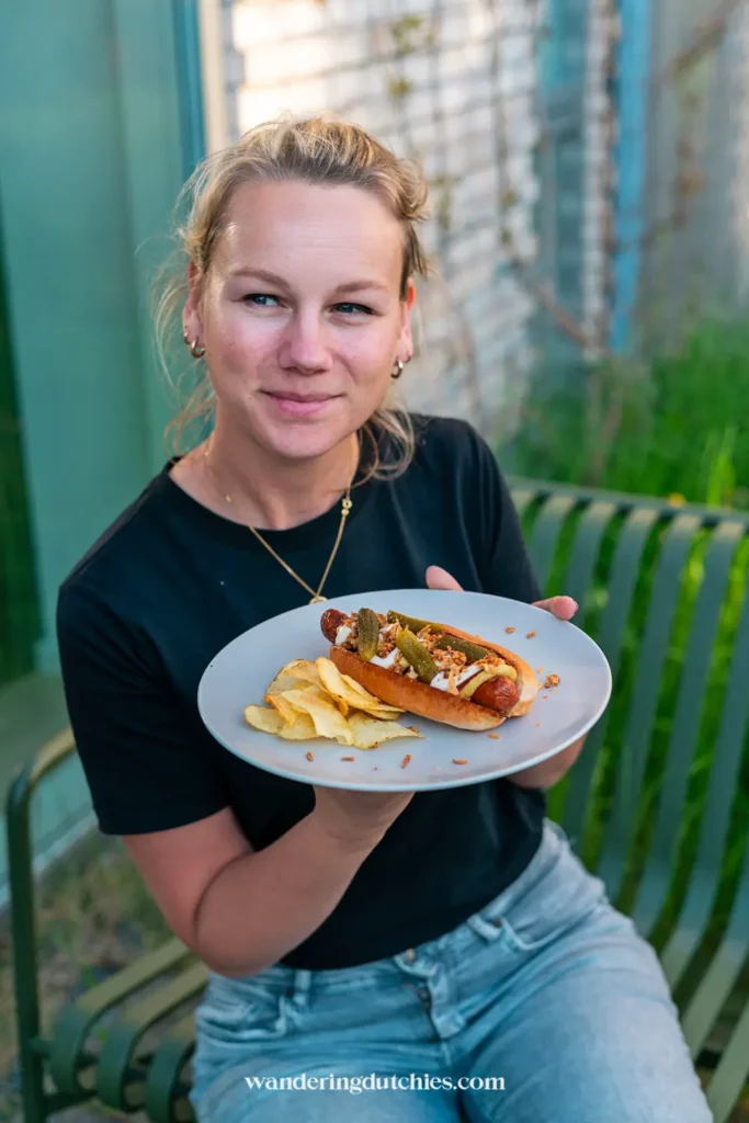 Marissa met een zelfgemaakte Deense hotdog en chips op een bankje in Kopenhagen