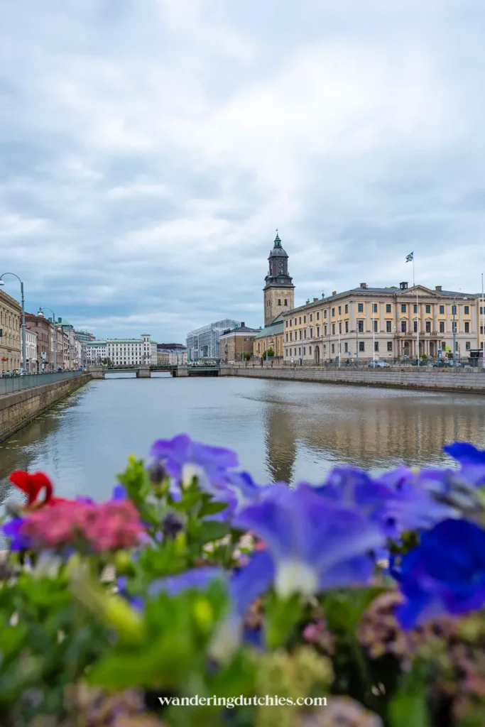 Uitzicht over het kanaal en de stad Göteborg met bloemen op de voorgrond en de Domkerk op de achtergrond.
