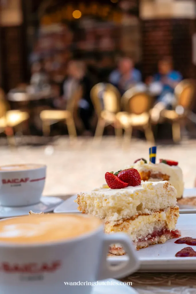 Koffie en taart tijdens een fika in Göteborg, met cappuccino en Zweedse aardbeientaart op een zonnig terras.