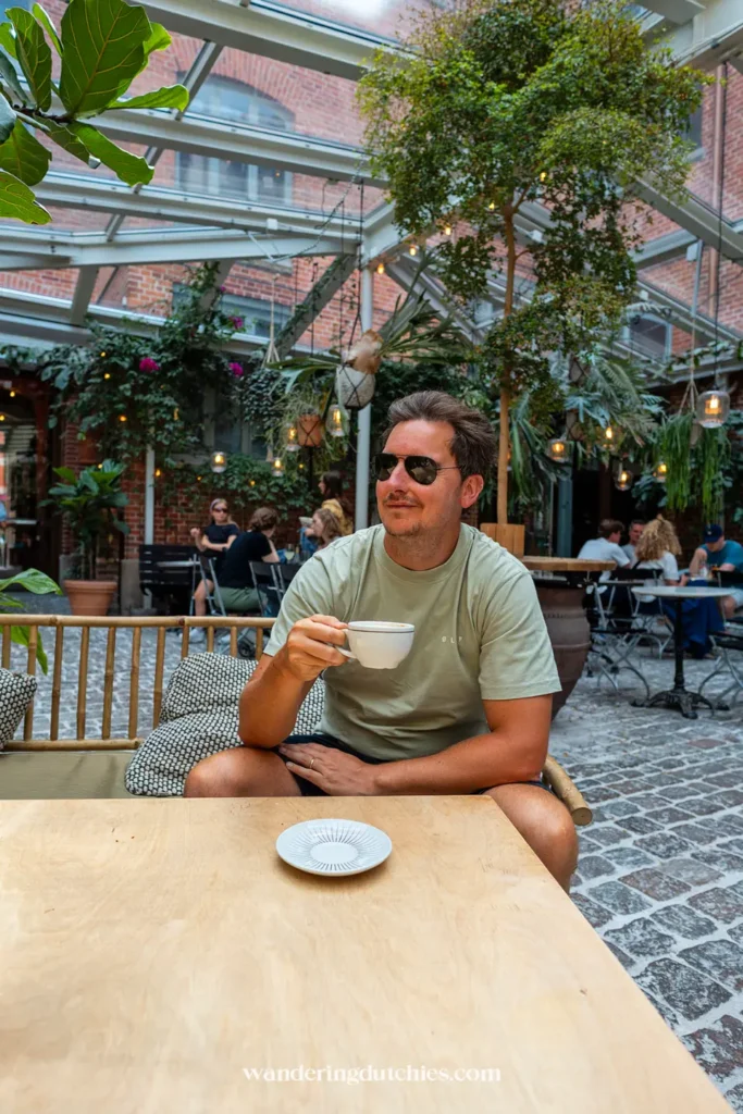Man drinkt koffie in de groene binnentuin van Kafé Magasinet in Göteborg.
