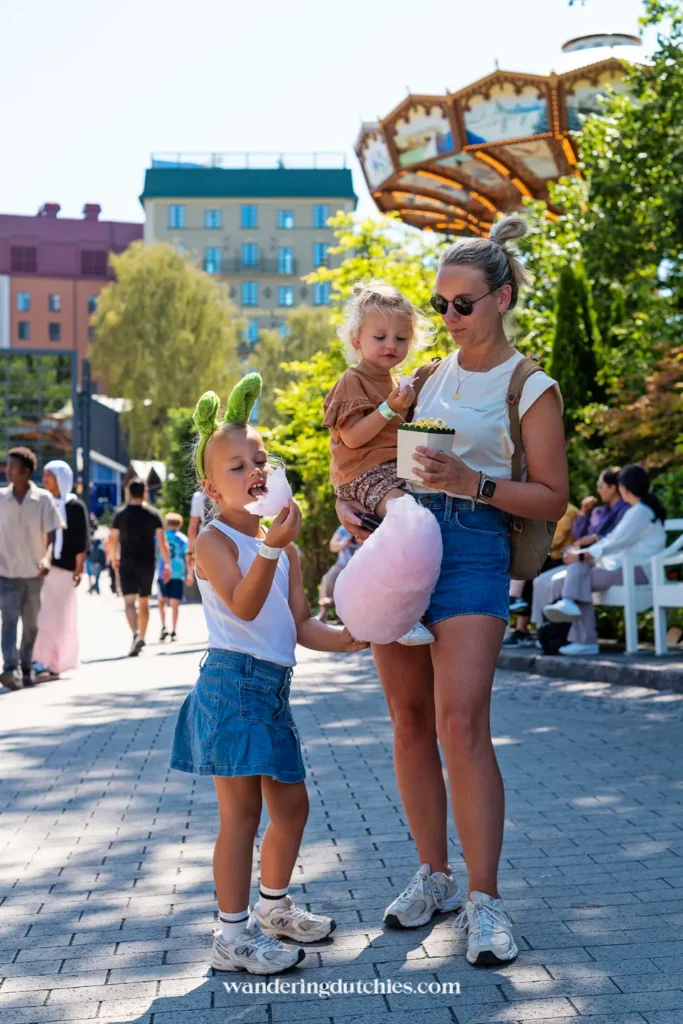 Moeder met twee kinderen eet popcorn en suikerspin in Liseberg tijdens een zomerdag in Göteborg.