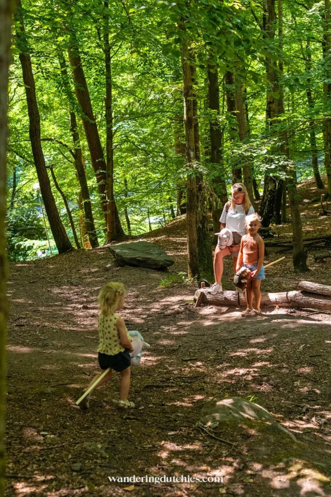 Gezin wandelt door het bos van Slottsskogen met stokpaardjes en speelgoed.
