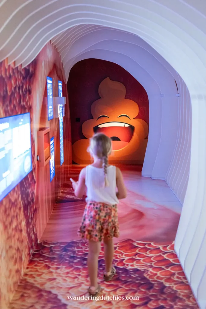 Kind loopt door interactieve tentoonstelling in Universeum Göteborg met kleurrijke verlichting en lachend emoji-figuur.